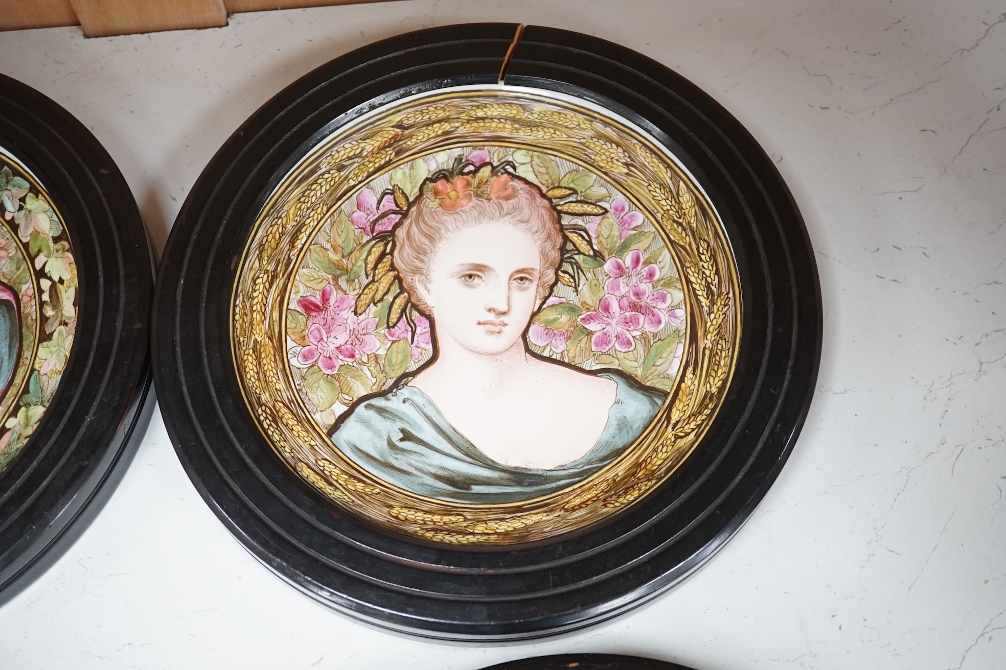 A set of four Copeland Spode Aesthetic period, outside decorated four seasons portrait plates, circa 1880, housed in ebonised wood frames, overall 31cm in diameter. Condition - fair, three frames cracked